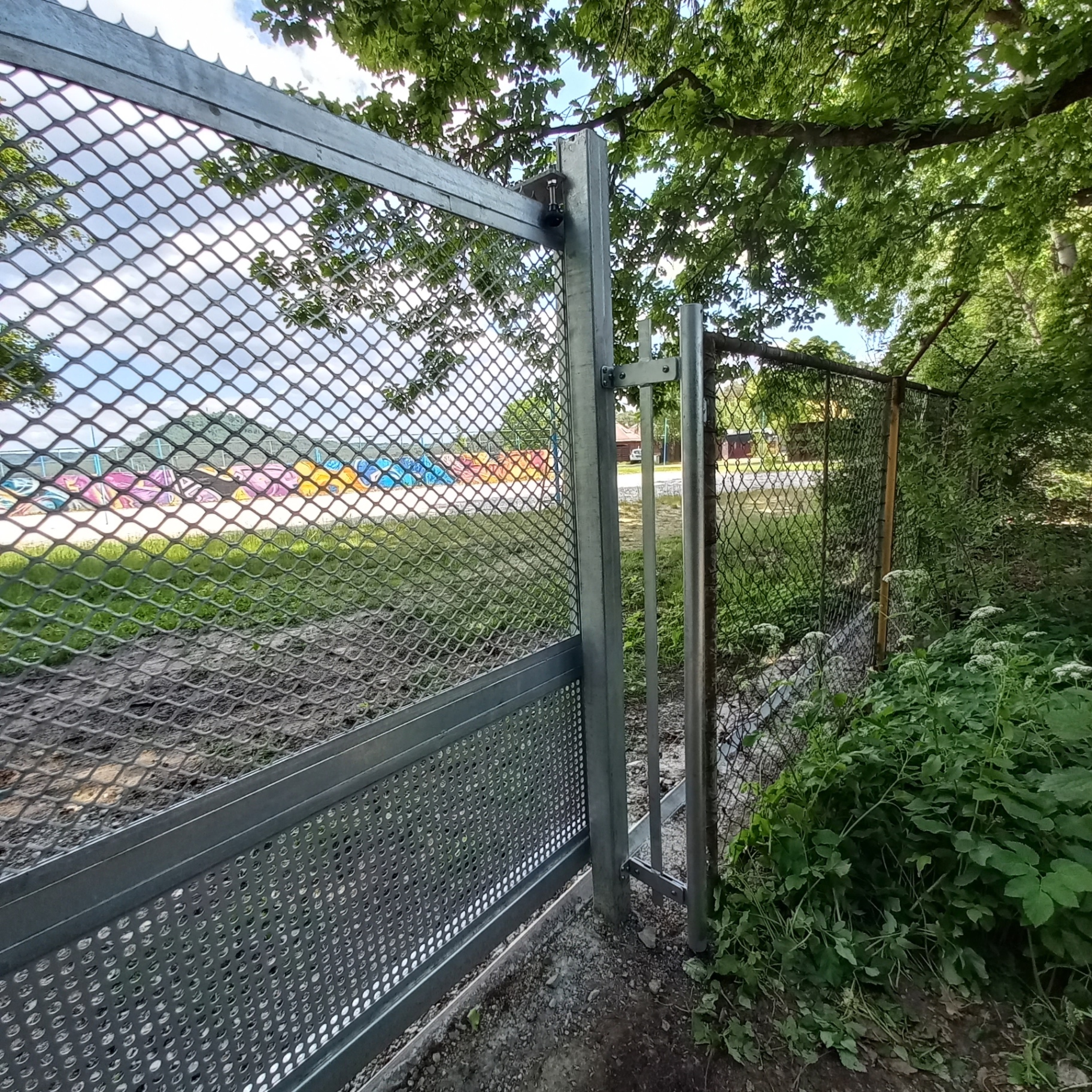 Samonosná brána — manuální — detail závěsů branky s tahokovem a děrovanou spodní výplní u zeleně