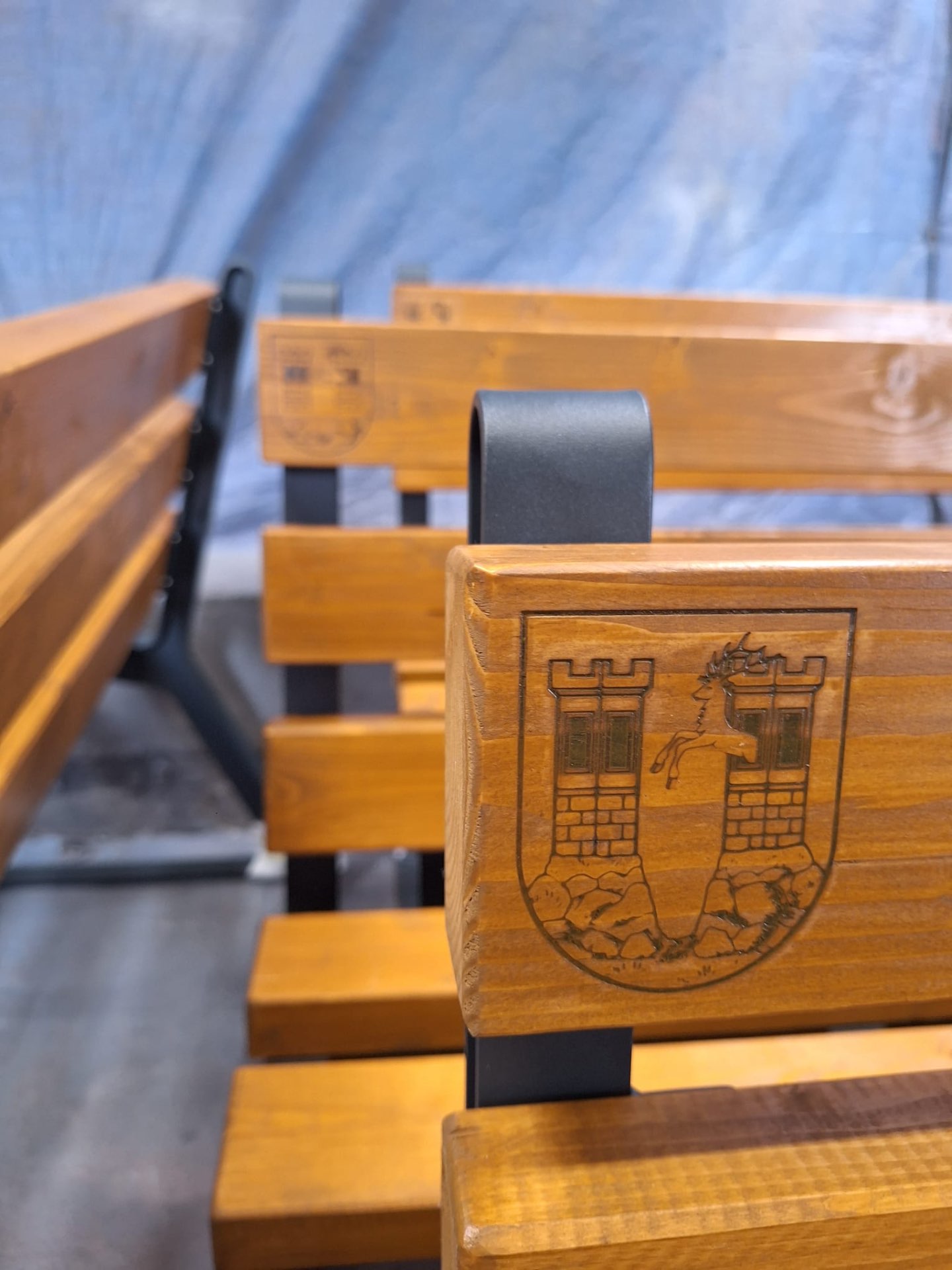Městský mobiliář — detail dřevěné bočnice lavičky s pískovaným městským znakem