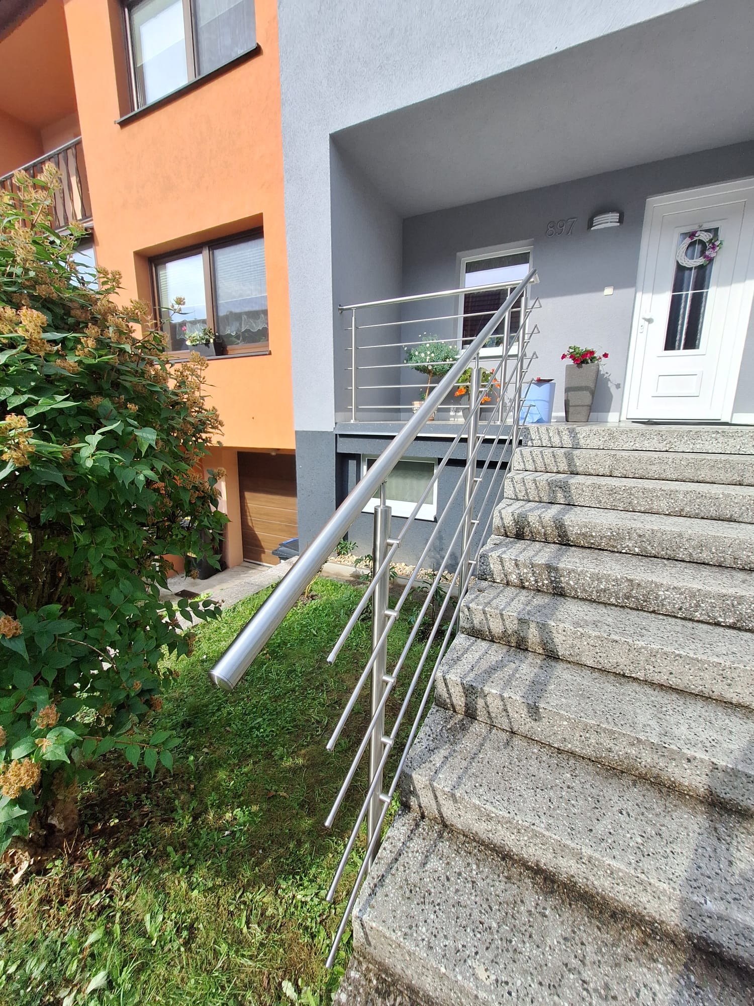 Nerezové zábradlí venkovního schodiště — šikmé madlo podél kamenných stupňů