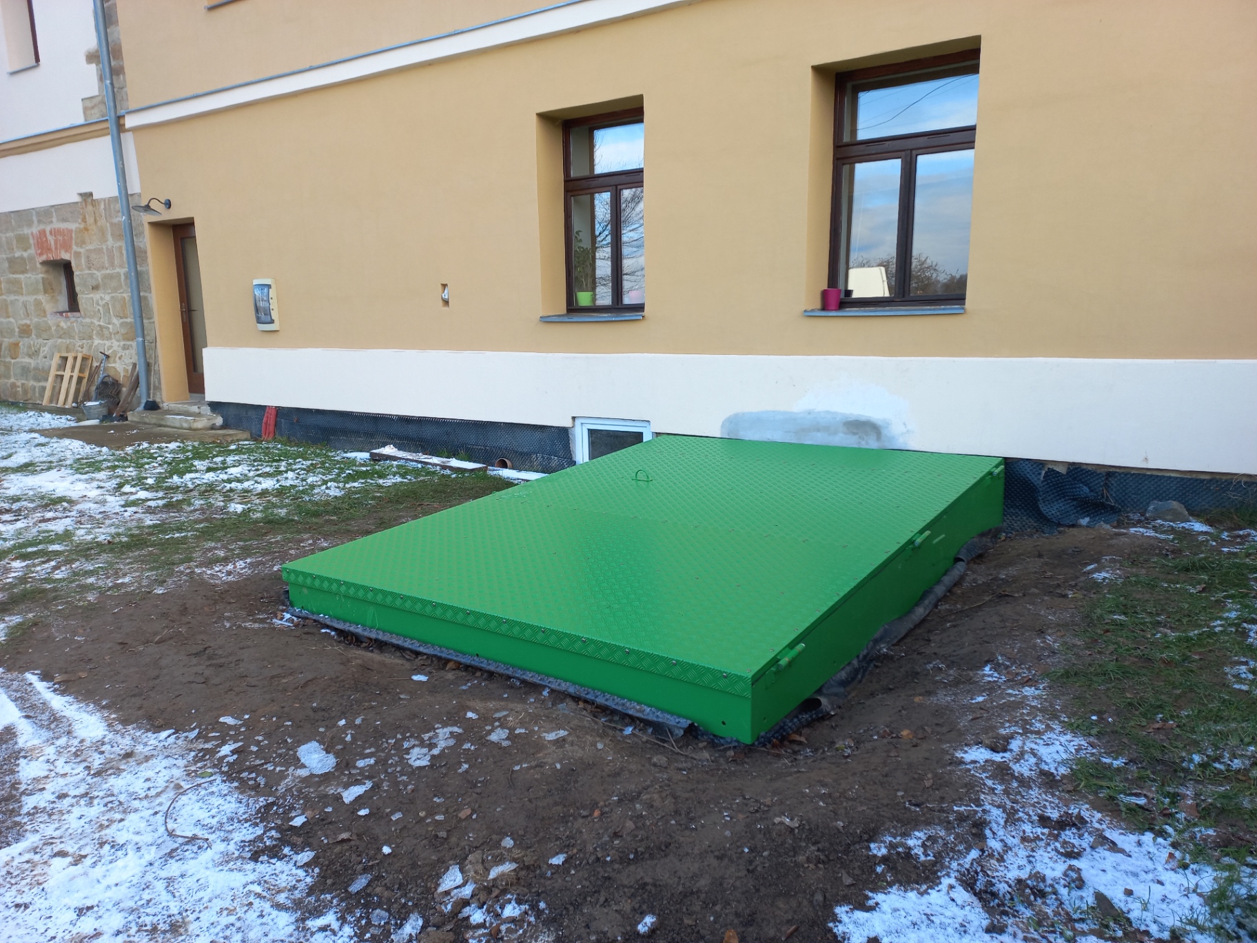 Poklop s pomocnými písty — celkový pohled na uzavřený ocelový poklop u domu